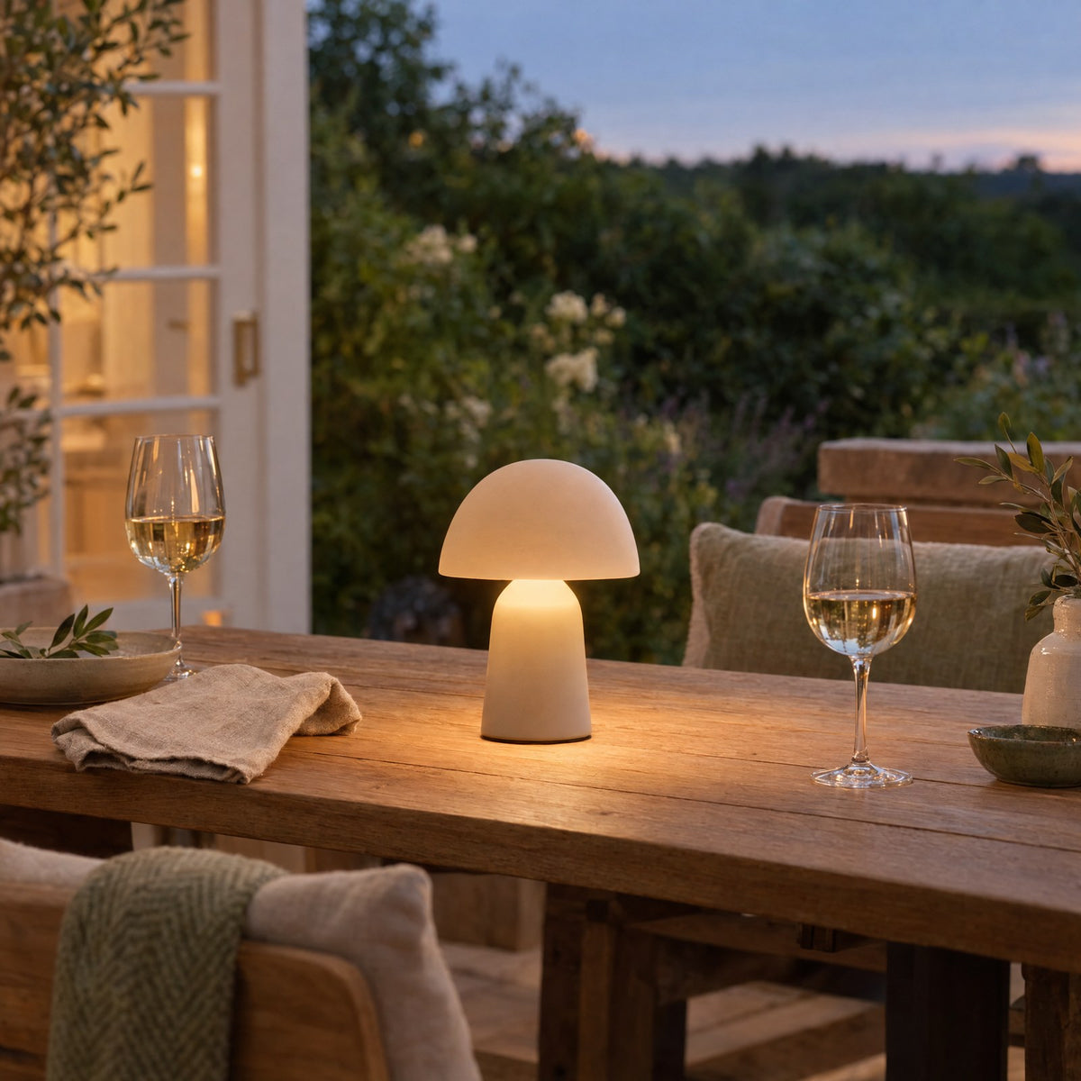 Small cordless lamp glowing on a terrace table at dusk