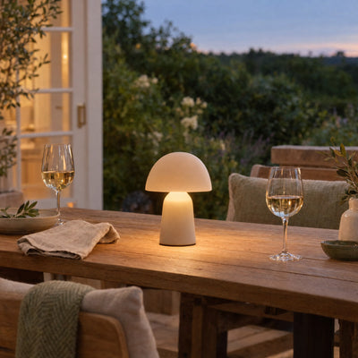 Small cordless lamp glowing on a terrace table at dusk