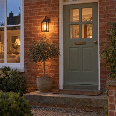 Outdoor wall lantern glowing beside a front door at dusk
